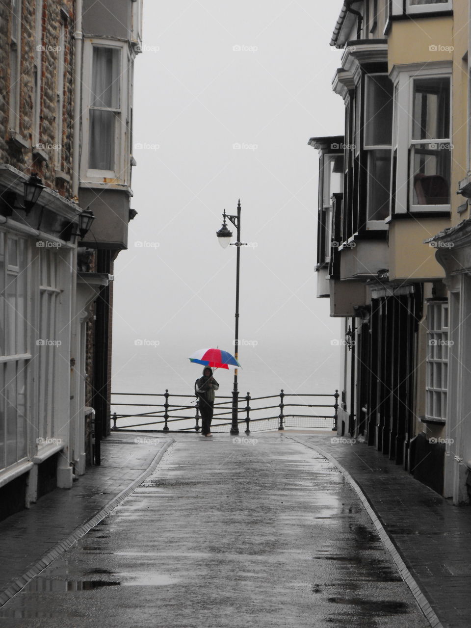 A man with a colorful umbrella by the sea