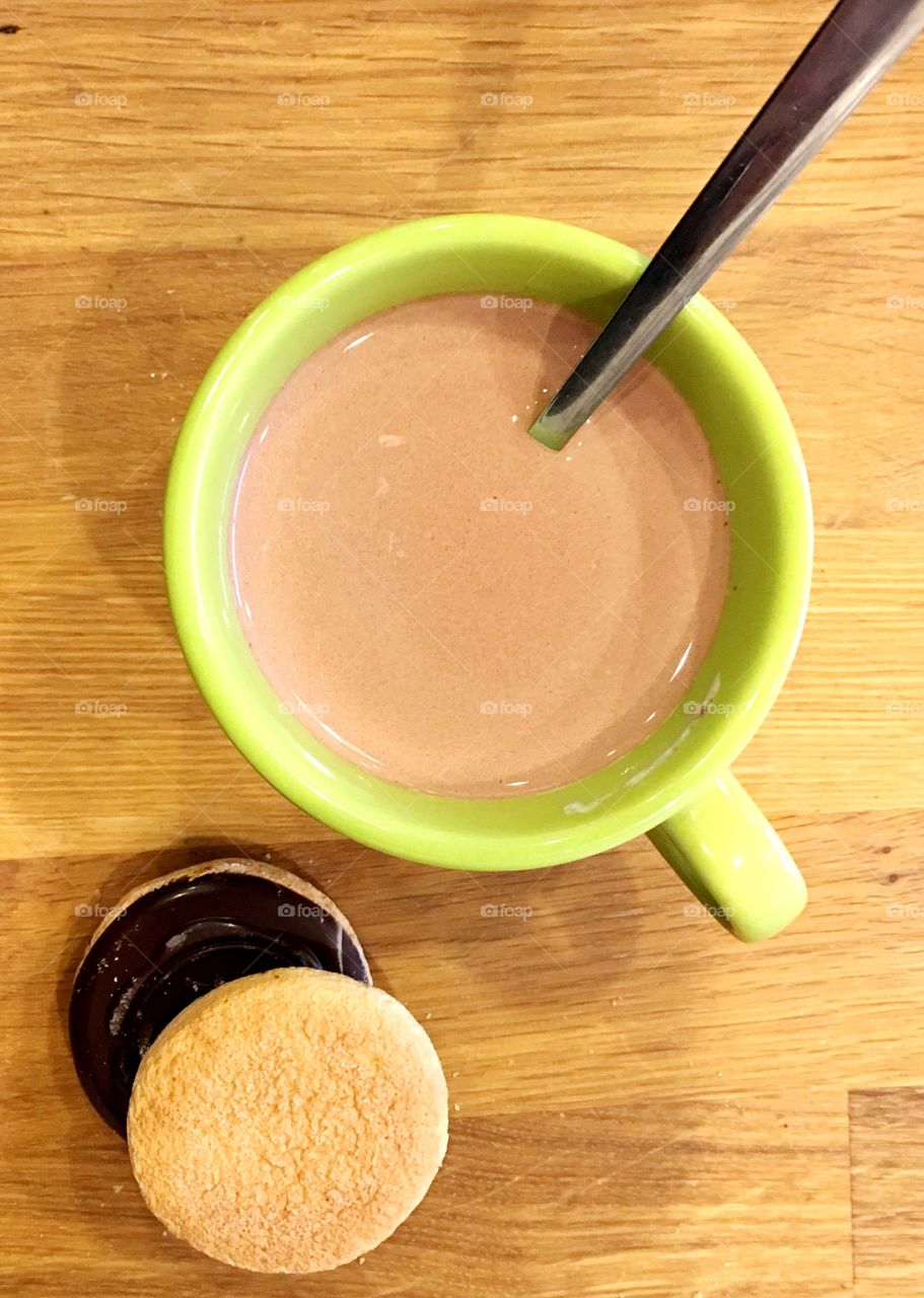 Hot cocoa in a green cup with cookies flat lay