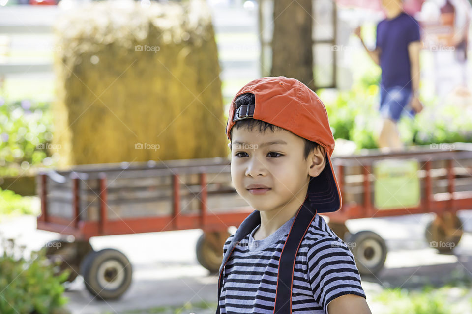 Portrait of Asian boy wearing a hat and smiled happily in park.