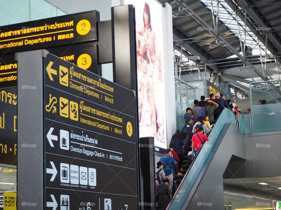 Passengers taking an escalator going to the immigration checkpoint in an international airport.