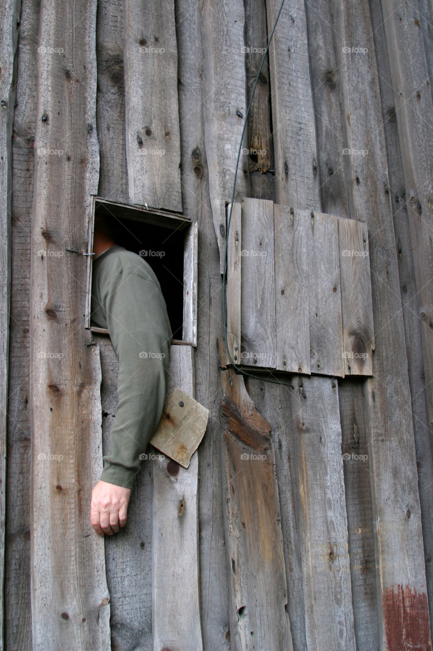 Arm in grey sweather hanging out of a window. 