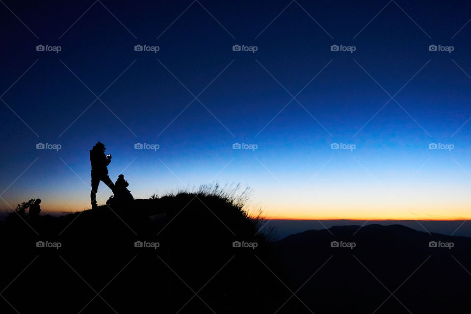 Silhouette picture of two people are waiting to see the sun. Landscape in twilight time. Sunset and sunrise around the world.