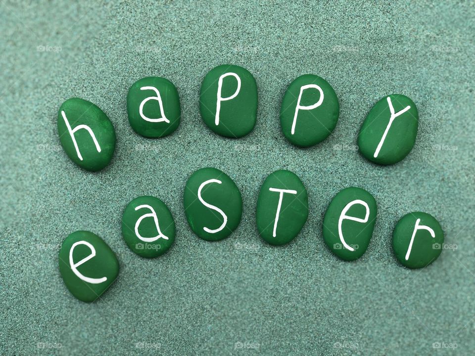 Happy Easter with green colored stones over green sand