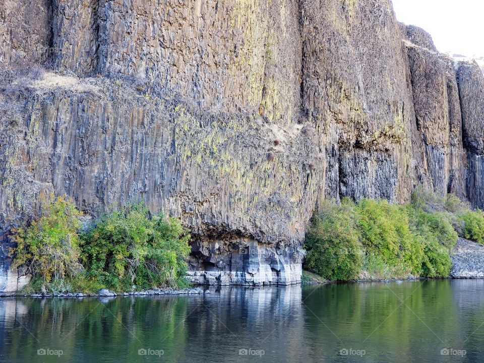 The beautiful Crooked River with fall colored bushes on its banks flows through a canyon formed from andesite and basalt flows on a nice autumn evening in Central Oregon. 