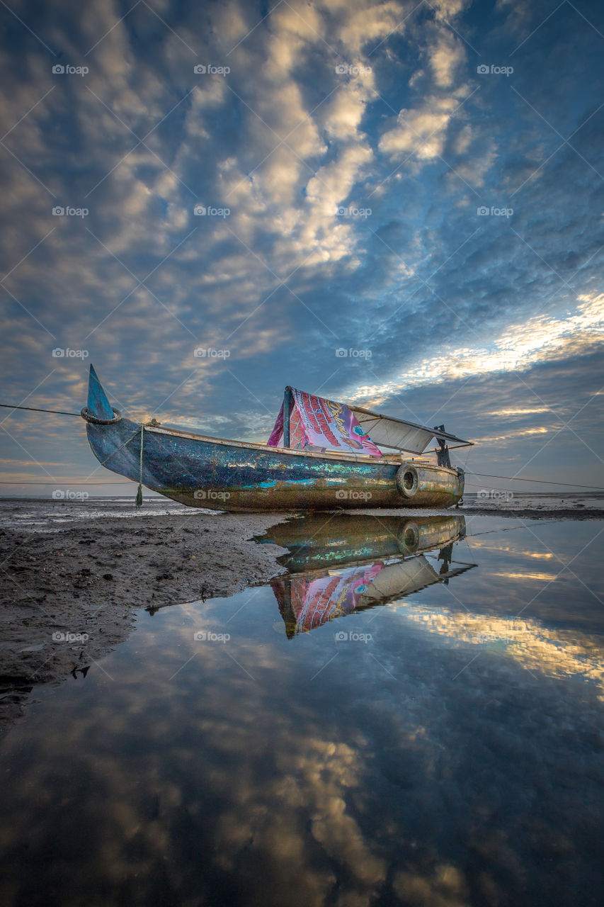 A boat and reflection of the cloud waves from the sky