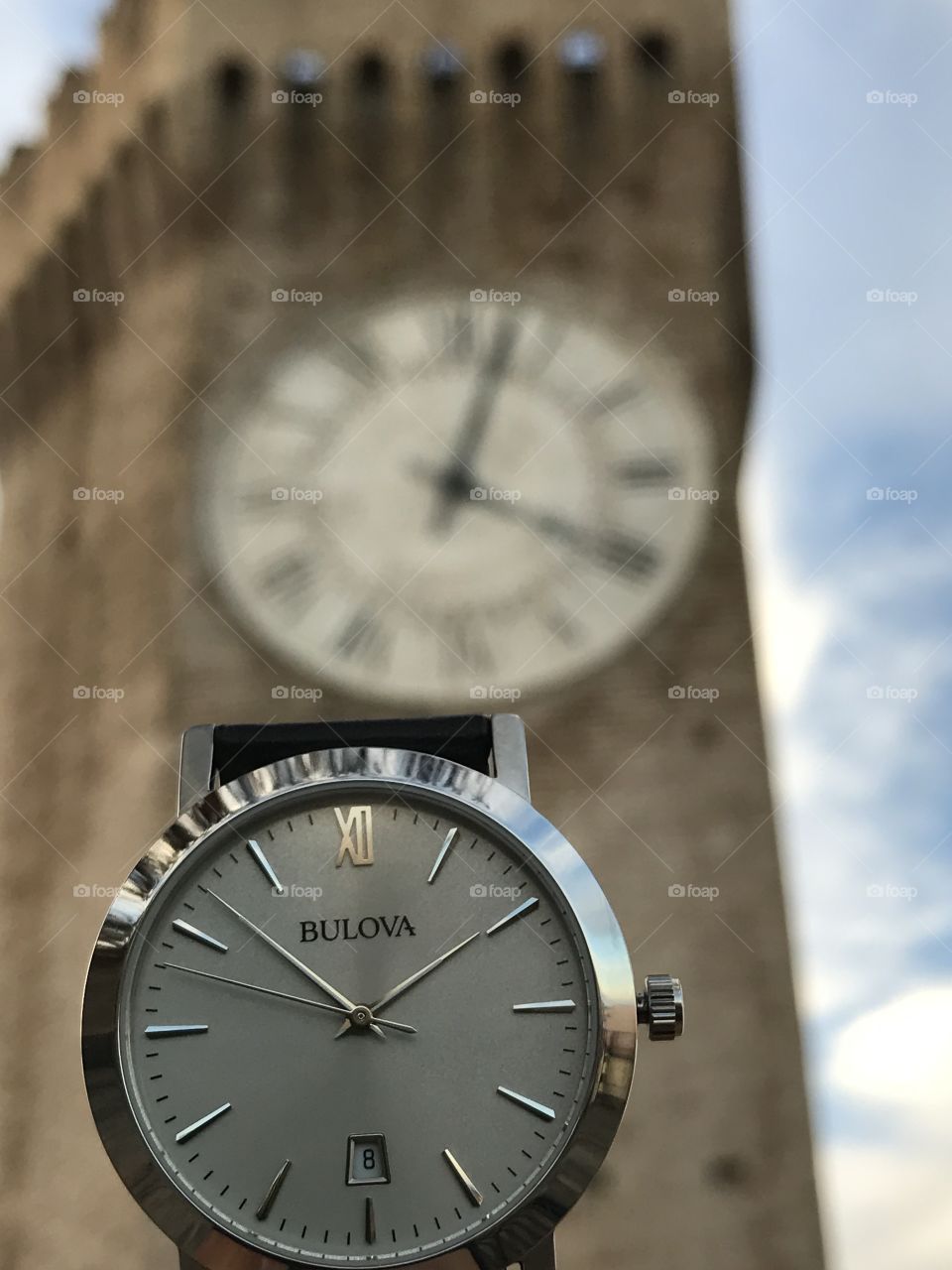 Bulova watch with historical clock tower behind 