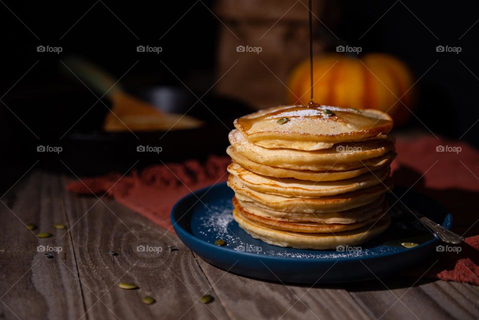 Dark and moody stack of autumnal pumpkin pancakes with a syrup drizzle 