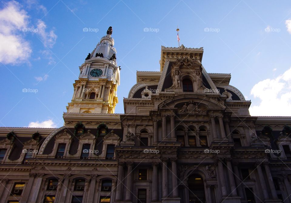 Entrance to Philadelphia City Hall building and clock tower with Quaker statue in morning light with blue sky
