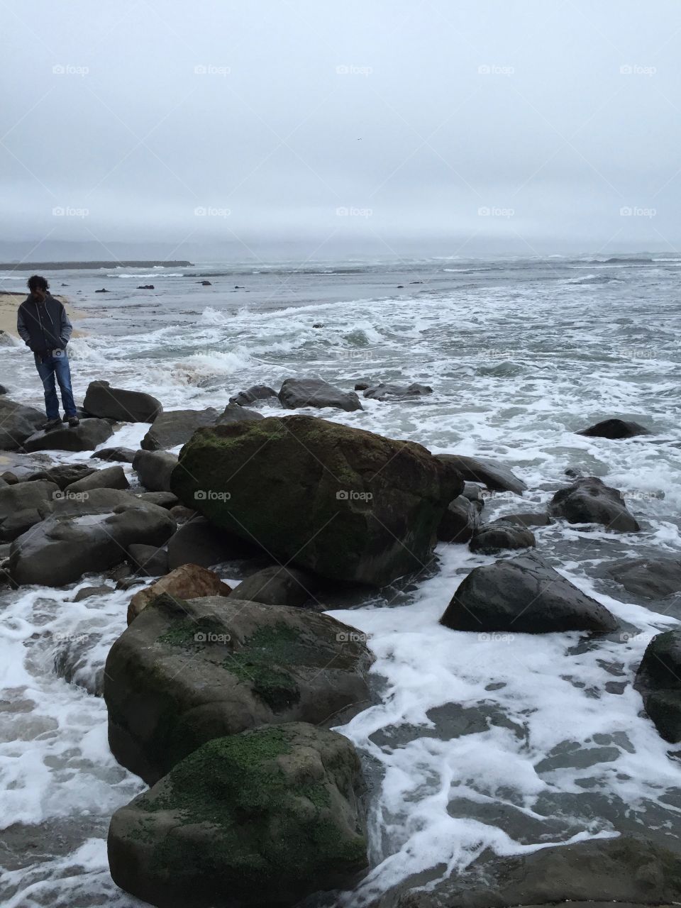 Tourists on rock, choppy ocean