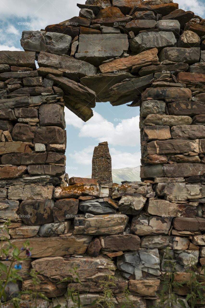 Ancient ruined medieval tower ruins against cloudy sky background .