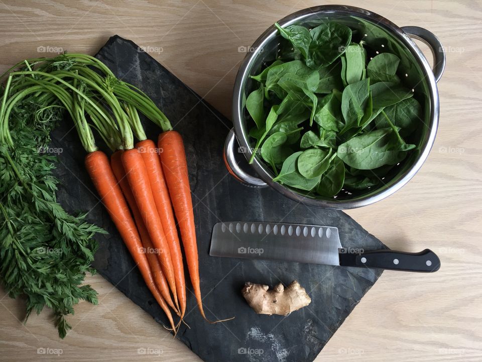 Cooking with fresh vegetables; baby spinach, organic carrots, ginger root. Healthy spring time meals.