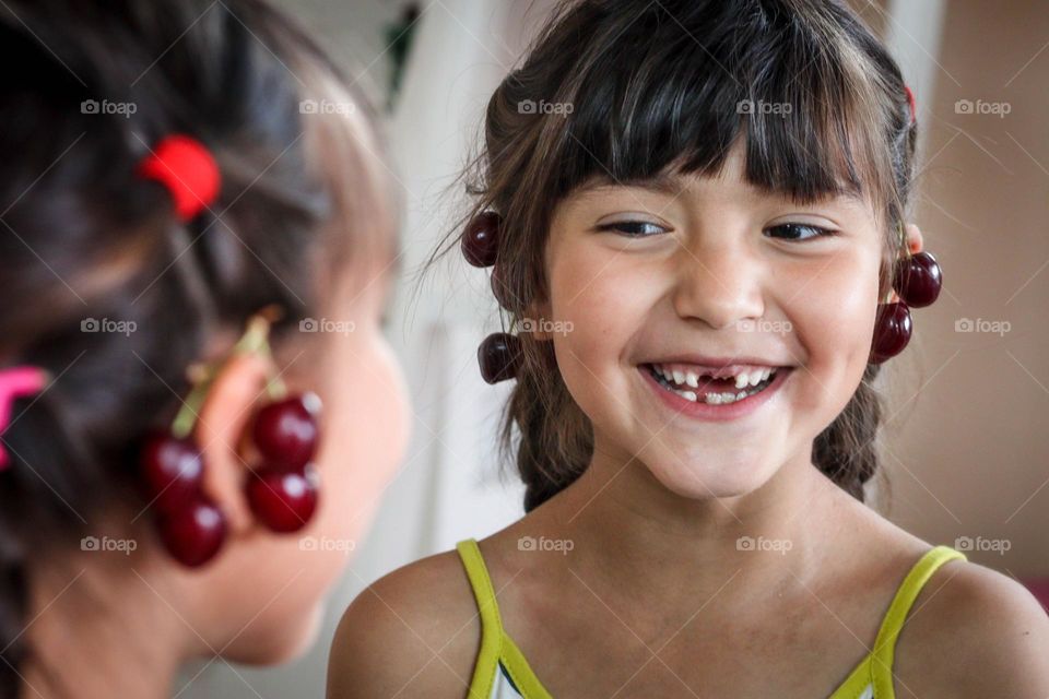 Cute little girl with earrings made of cherries