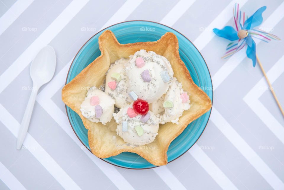 Flat lay of a taco bowl filled with ice cream, sprinkles and a cherry on top 