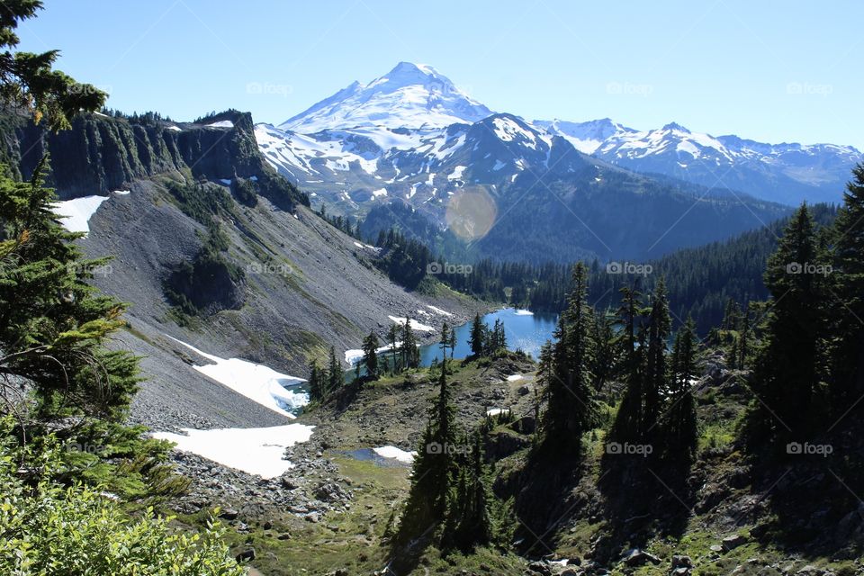 Mt. Baker from the highest point in a 8 mile hike viewing the melting snow, bright blue lake, and snowy mountain peak.
