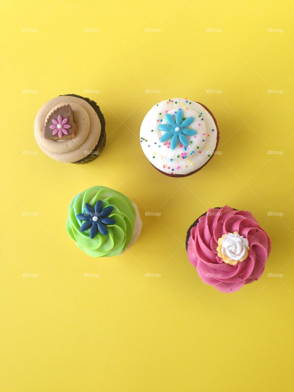 Top view of brightly colored cupcakes on a yellow background