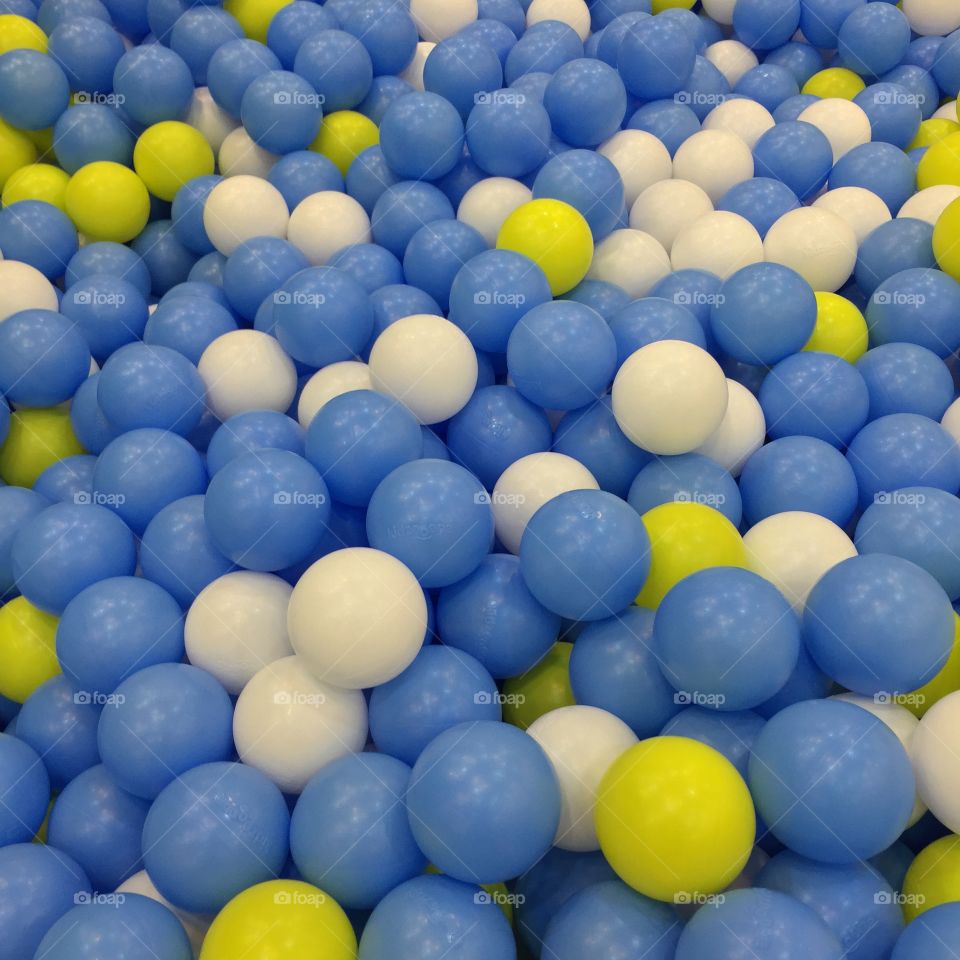 Blue, white, and yellow balls in a ball pit.