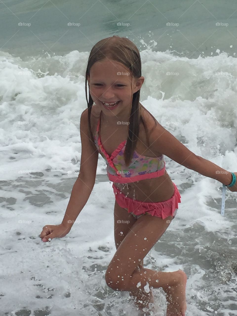 Little girl playing in the waves of the ocean