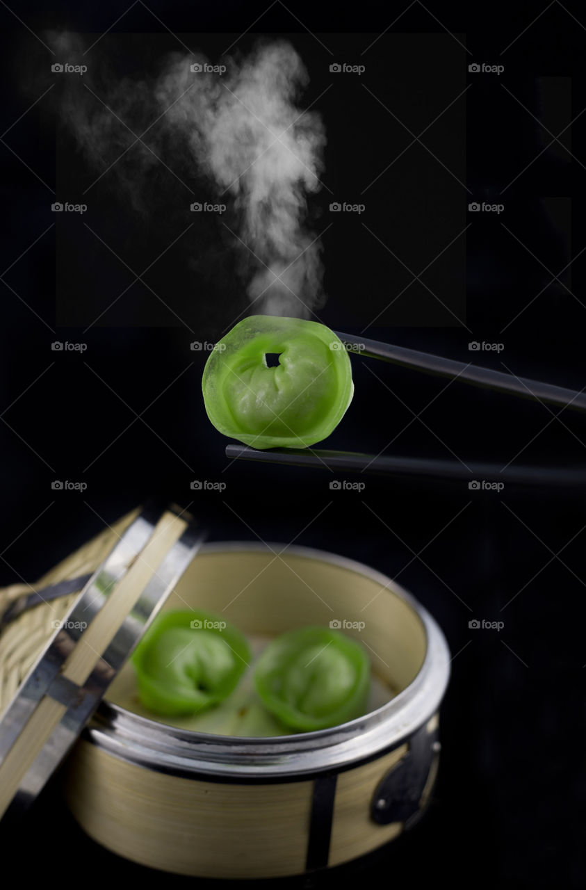 close-up shot of a hot green dim sum with steam, isolated on a black background