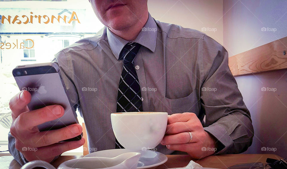 Smart suited business man working through lunch break on smart phone. staying in touch.