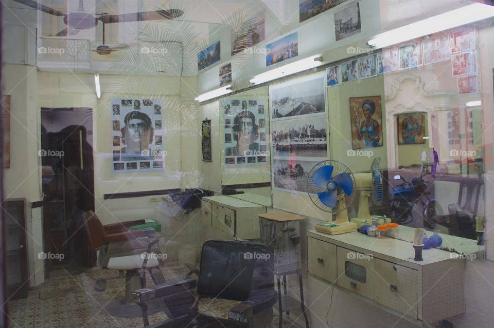 An image of the inside of a barbershop in Havana, Cuba as seen looking in through the front window.
