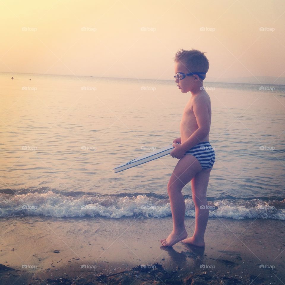 Boy and the Sea. boy standing on the beach in the sunset