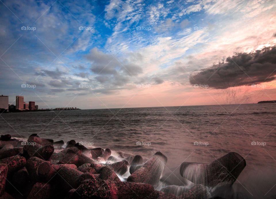 magical sunset by marine drive of Mumbai city with the waves hitting the rocks at rhythm.