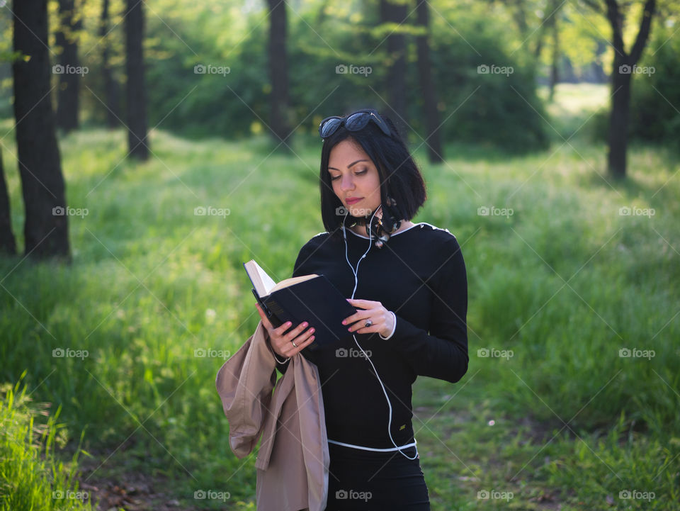 Beautiful woman reading book in the forest or park 