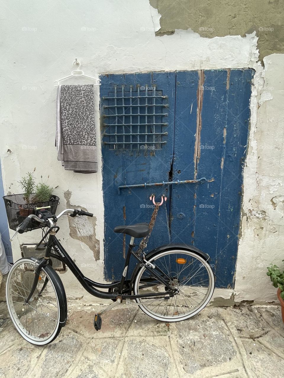 Lonely bike locked to a blu painted door 