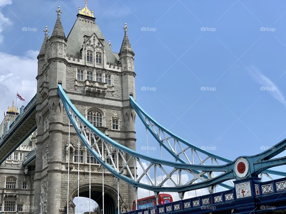 London’s bridge on a sunny day, with red bus going through it 