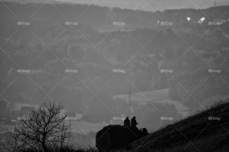 Two people sitting on a rock in a landscape