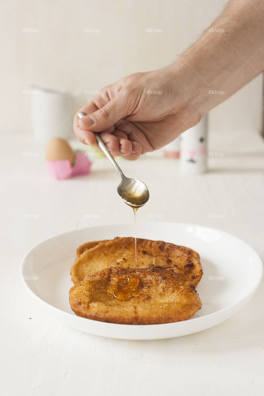 Pouring honey on Torrijas. Pouring honey on Torrijas, Spanish style French toast. Traditional recipe for Easter. Delicious food.