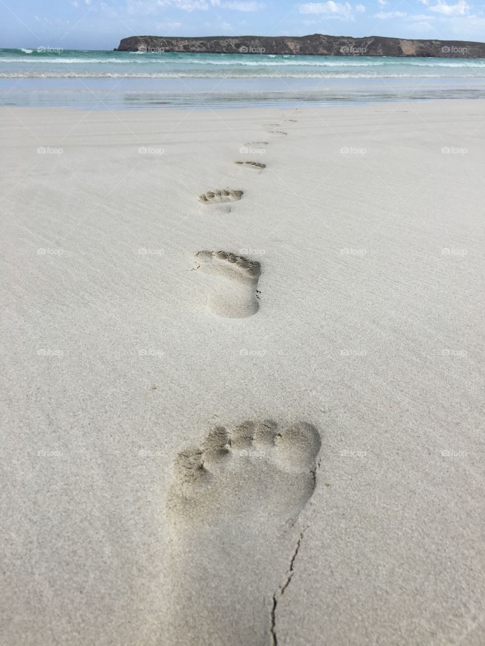 Footprints in the sand on remote beach