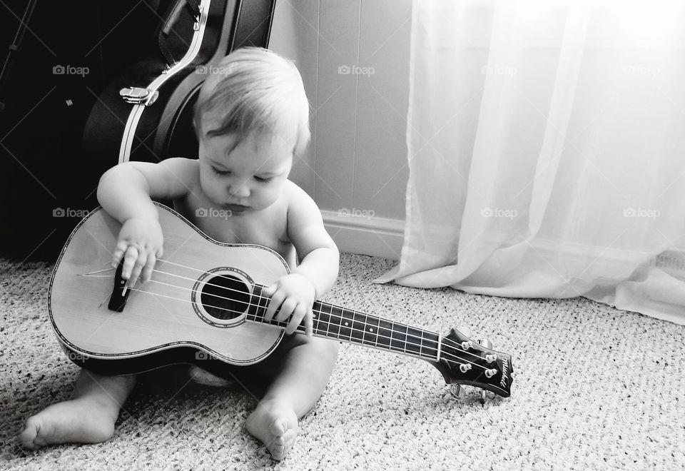 Baby boy playing a ukelele- black and white