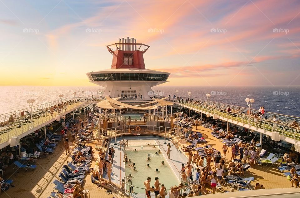 People enjoying the pool of a cruise at sunset