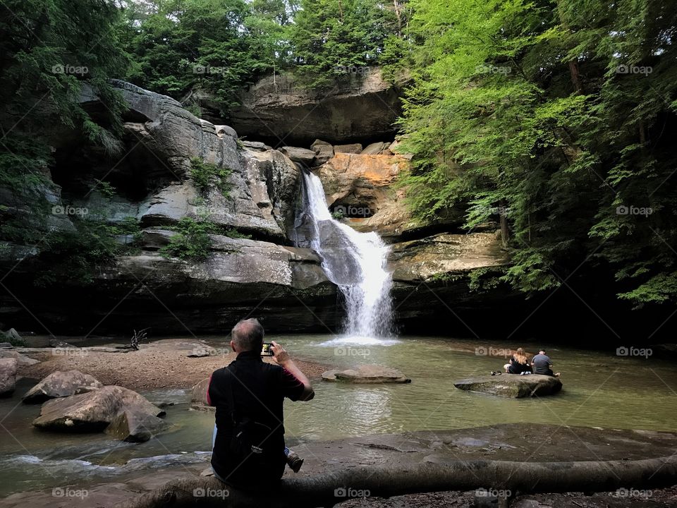 Photographer taking photograph of waterfall