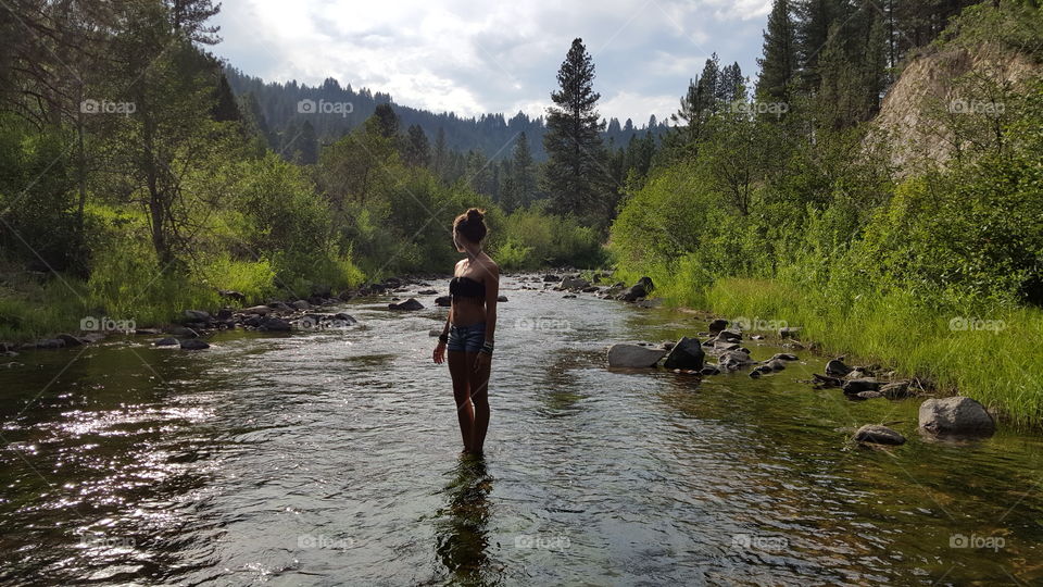 Woman of the Water. A woman standing in Grimes Creek, peering off into the mountainscape backdrop.