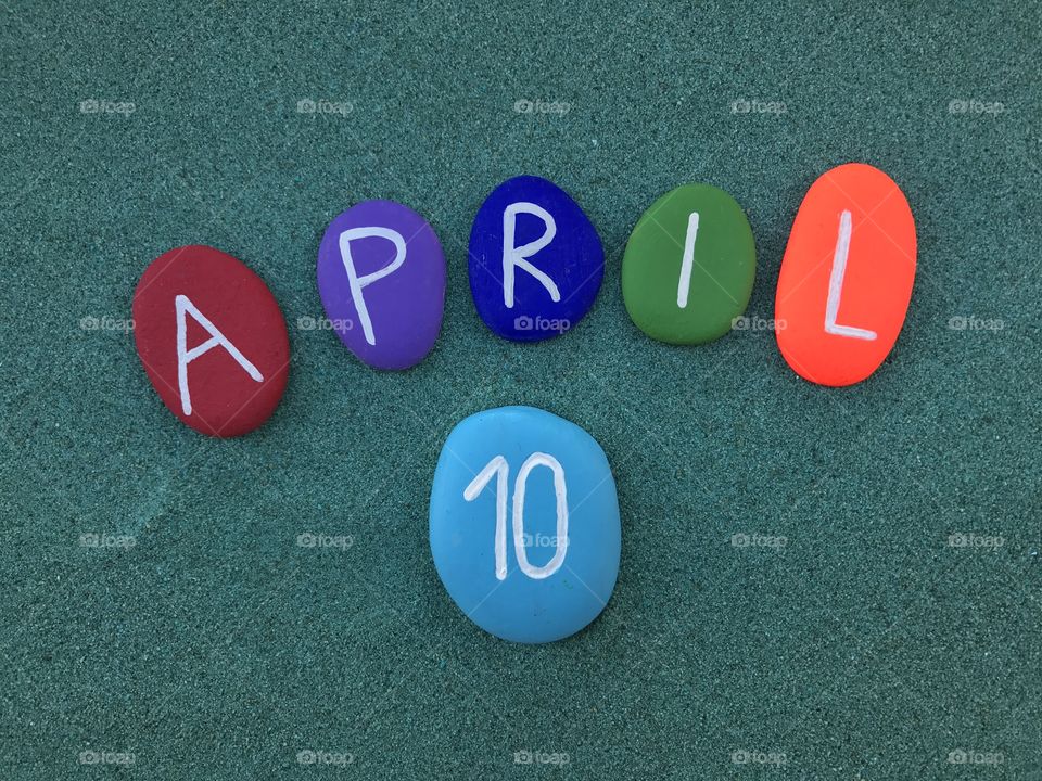 10 April, calendar date on colored stones over green sand 