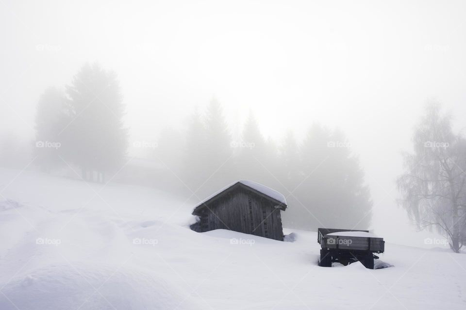 Photo of a small cottage or house in mountains during winter and snow 