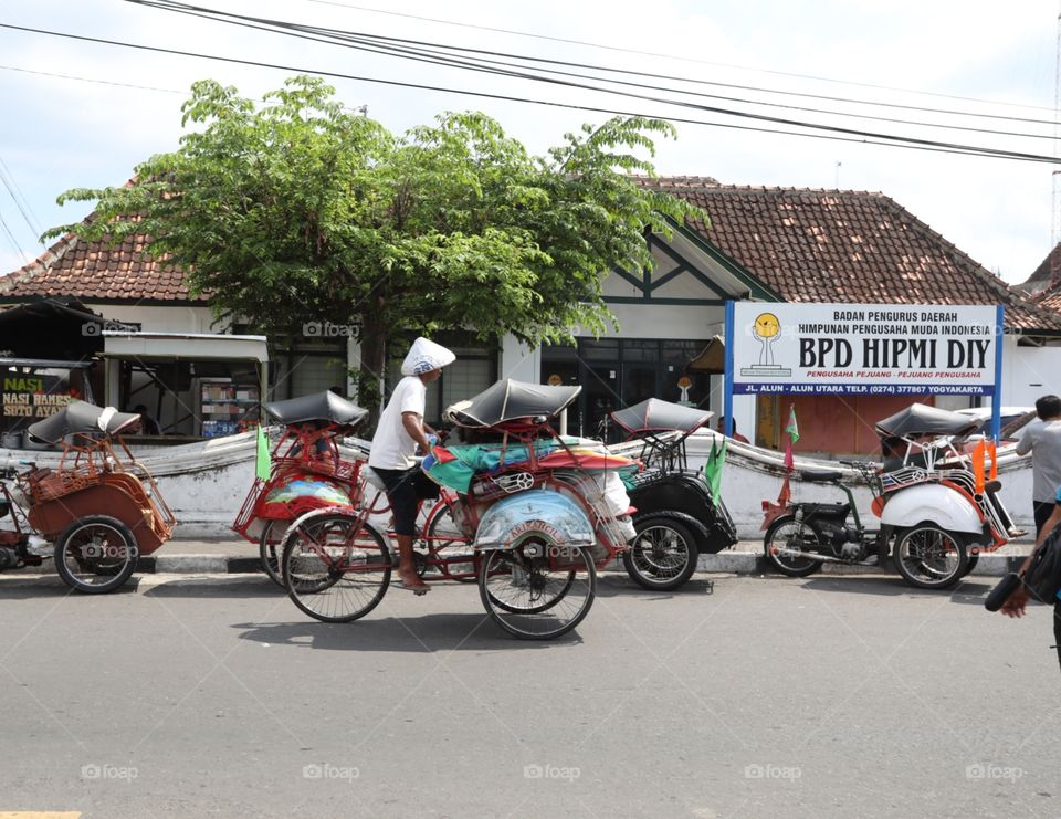 A rickshaw makes its way through a street near the Sultan's Palace in Yogyakarta, Indonesia