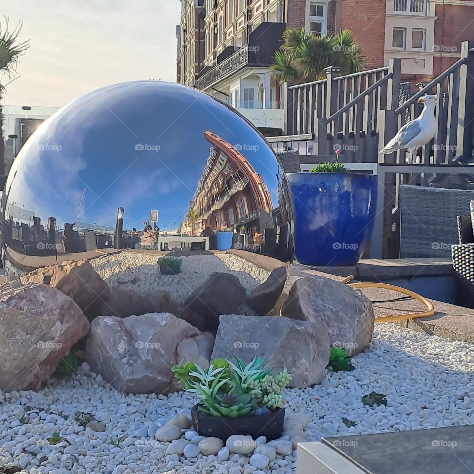 shiny sphere reflecting light and surroundings. seagull on wall buildings around. cool autumn afternoon by the sea U.k