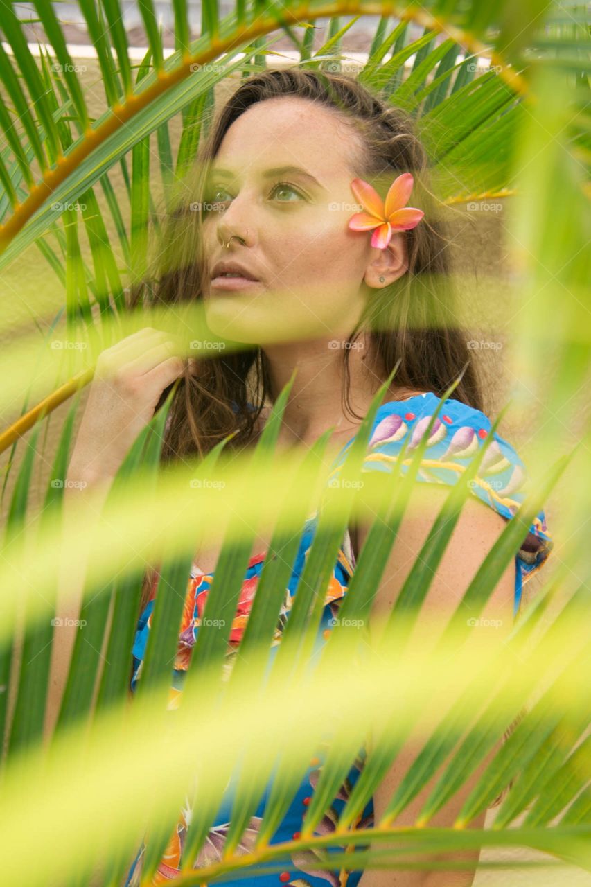 Beautiful woman in Hawaii behind fern with flower in hair