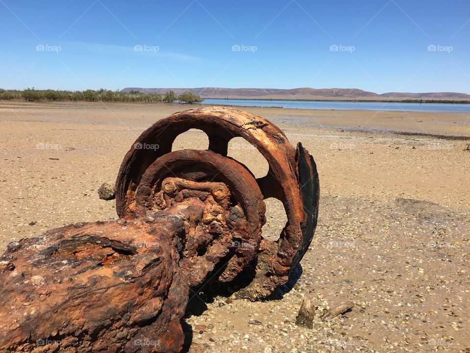 Rusted wheel machinery washed up on Australian shore at low tide 