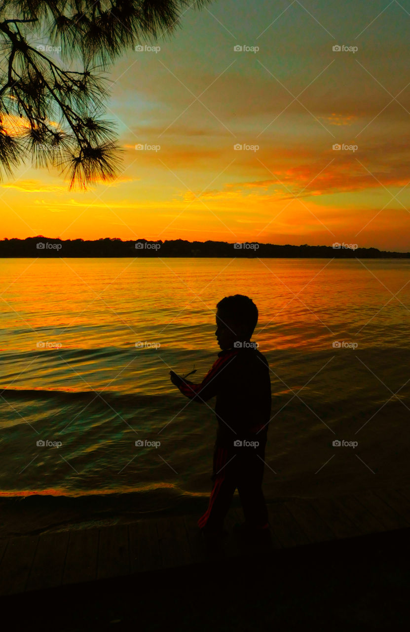 A boy looks out over the bayou at the magnificent sunset!