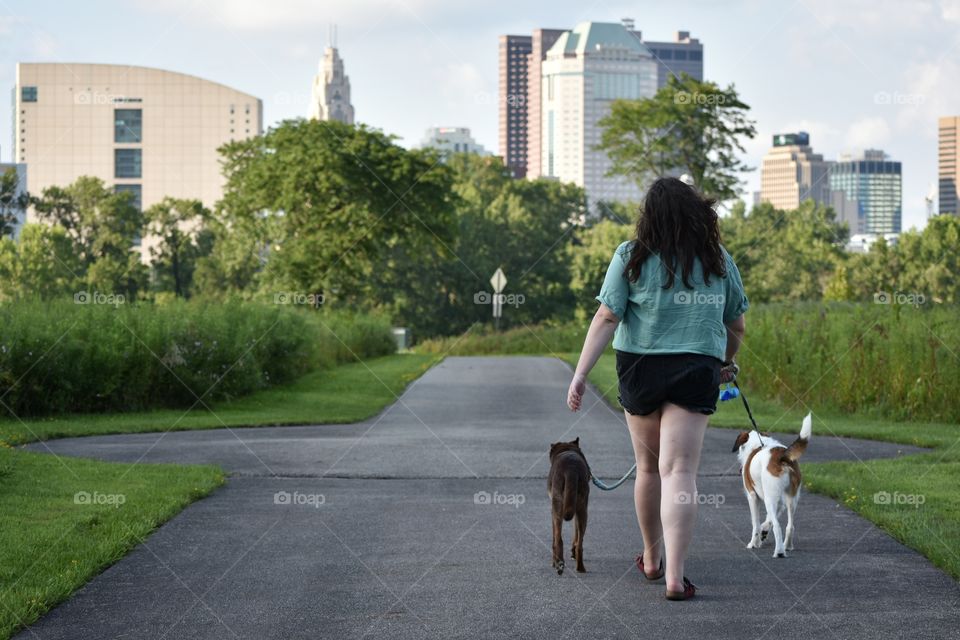 Woman walking in urban nature park with 2 dogs 