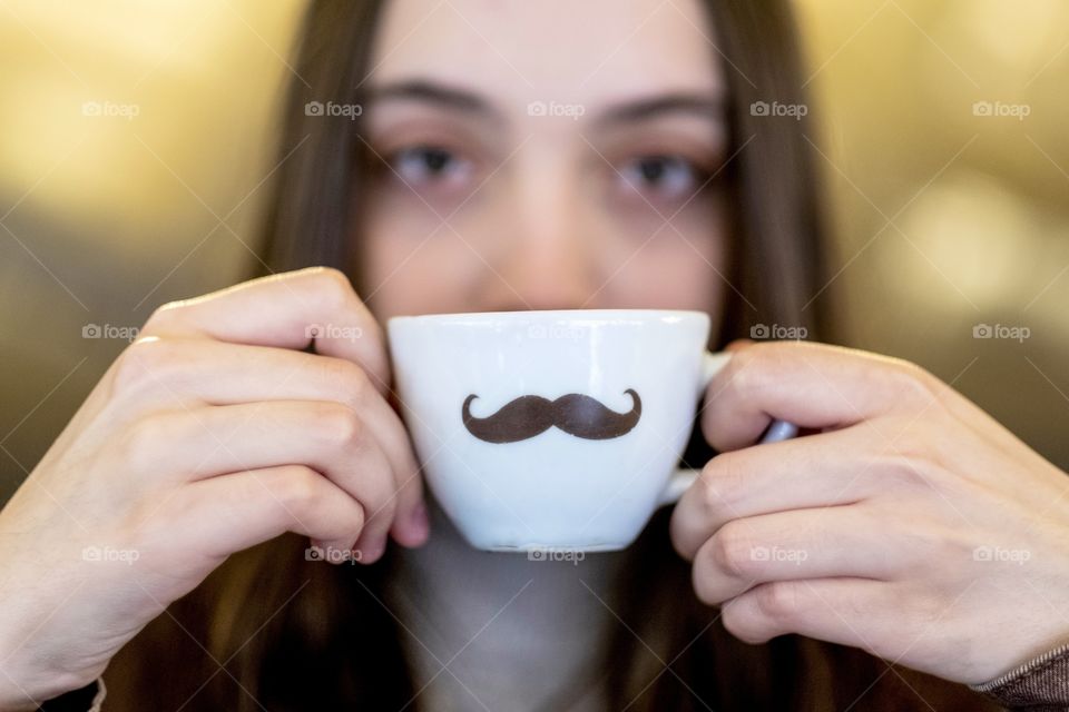 holding a coffee cup with a moustach