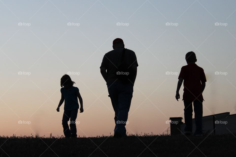 Evening Walk. Father and children at dusk