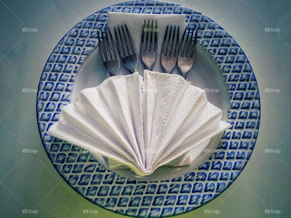 a white paper fan garnished by forks on a plate.