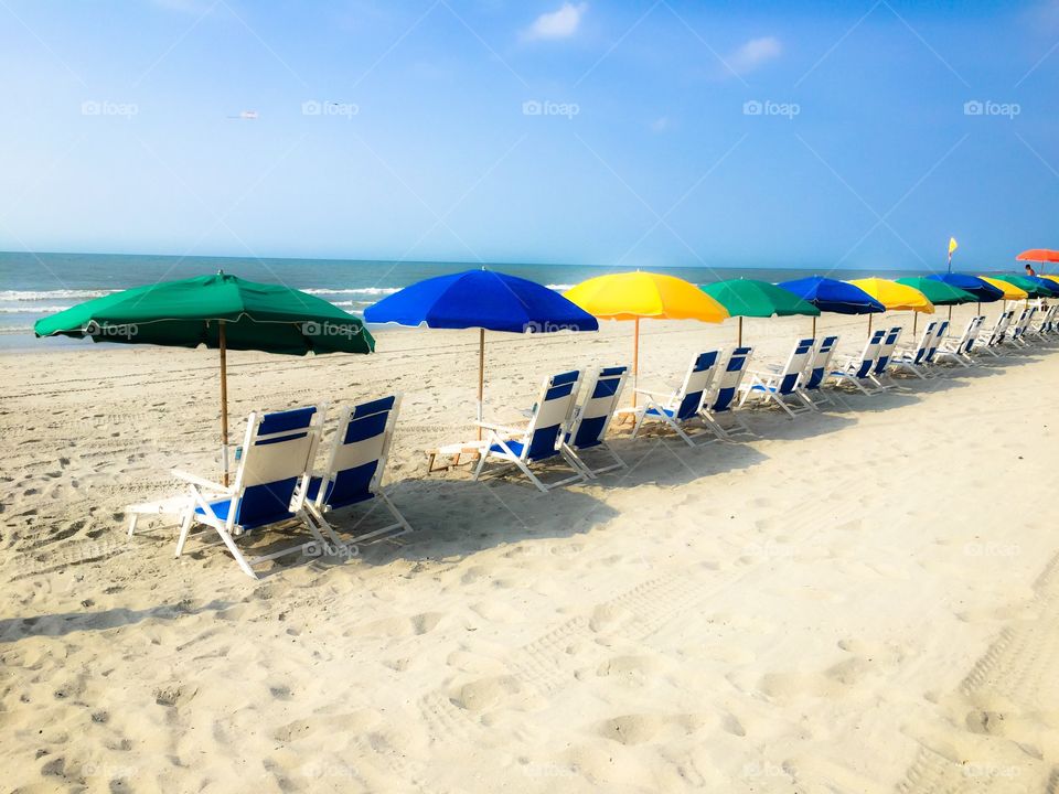 Beach chairs. A beautiful summer day at the beach with rental chairs lined up waiting for customers relax.