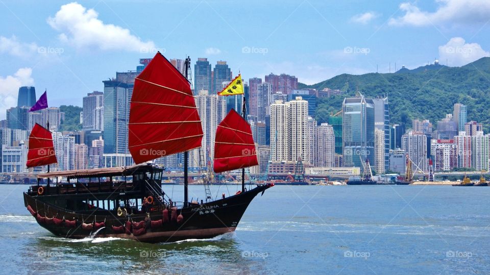 The Aqua Luna junk cruises through the waters of Victoria Harbour near the high rises of Hong Kong 