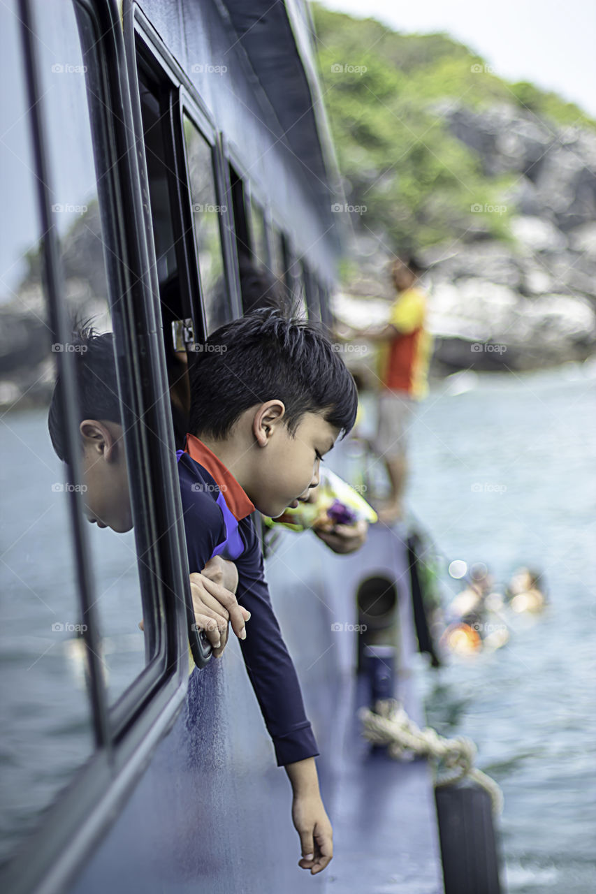 Portrait of Asia boy on the window boat in the sea.